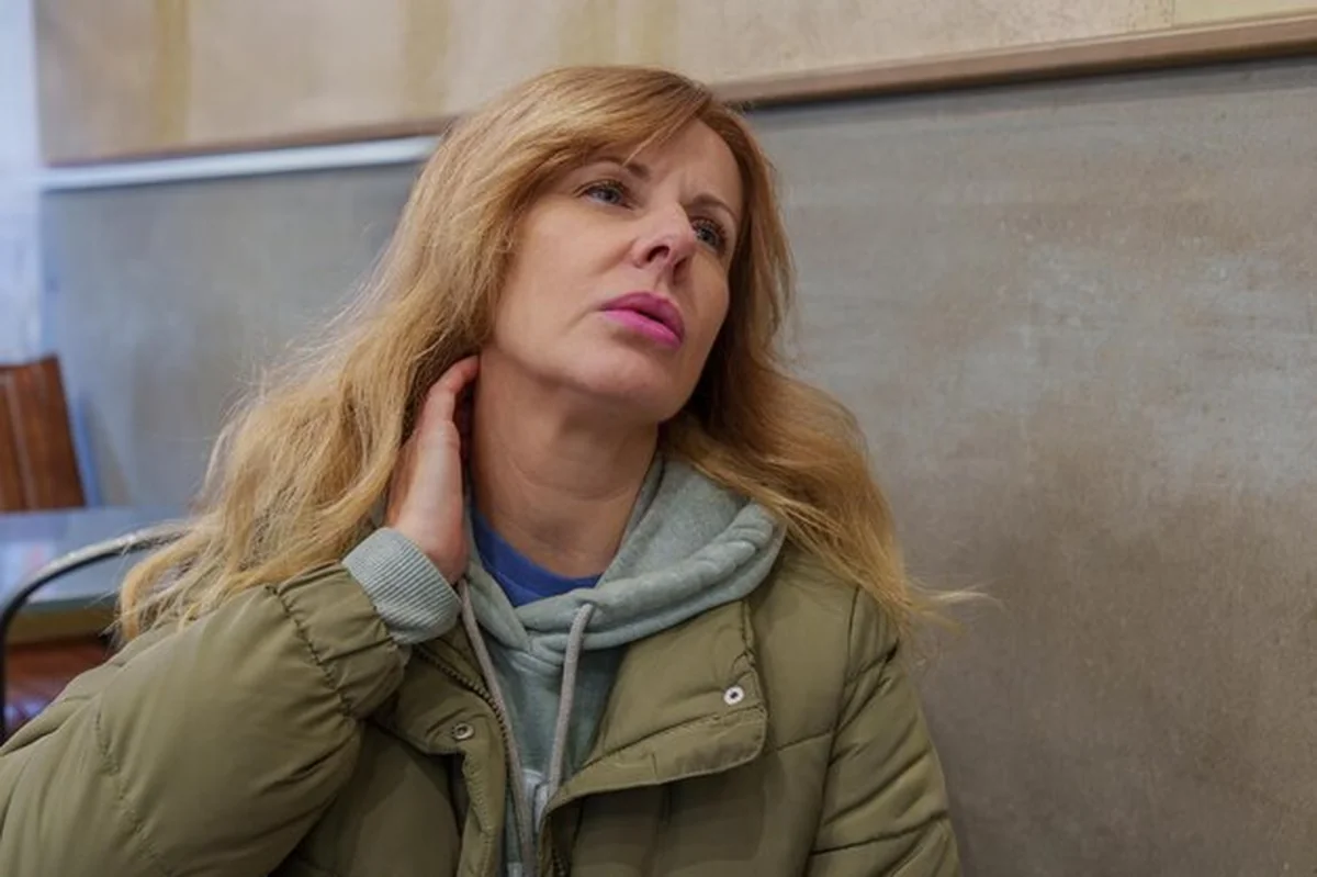 Kobieta z dyskomfortem szyi siedząca w publicznej przestrzeni wewnętrznej