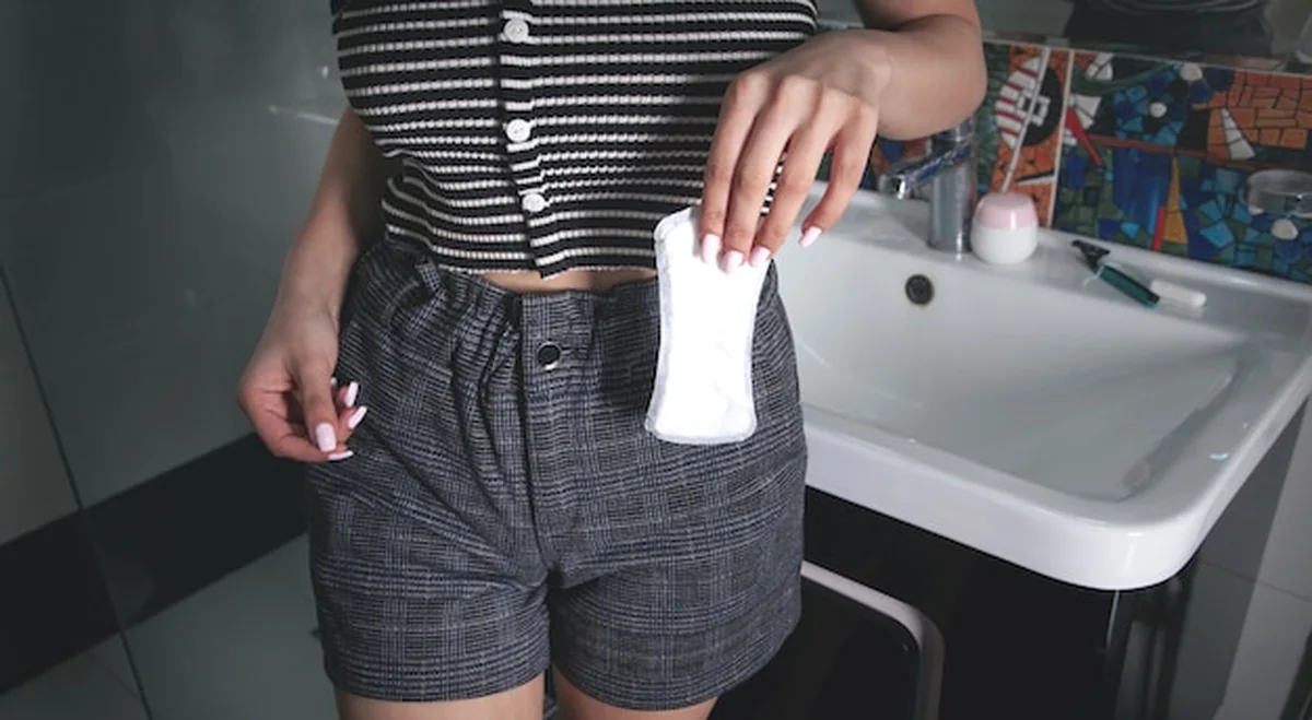 Kobieta trzyma podpaskę menstruacyjną w łazience