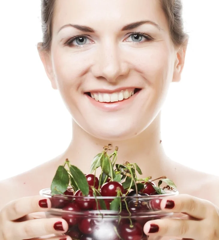 Kobieta trzymająca czereśnie na białym tle