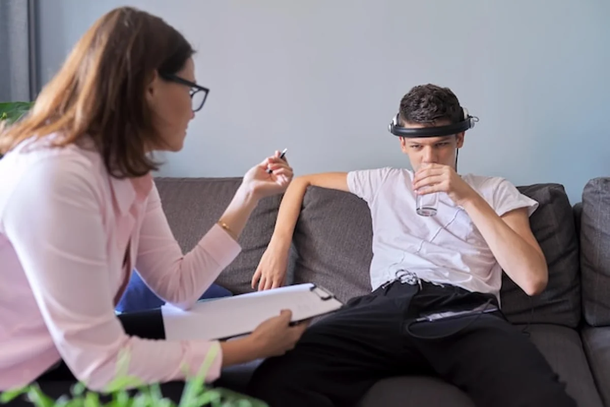 Nastoletni chłopiec rozmawia z psychologiem w biurze podczas sesji terapii