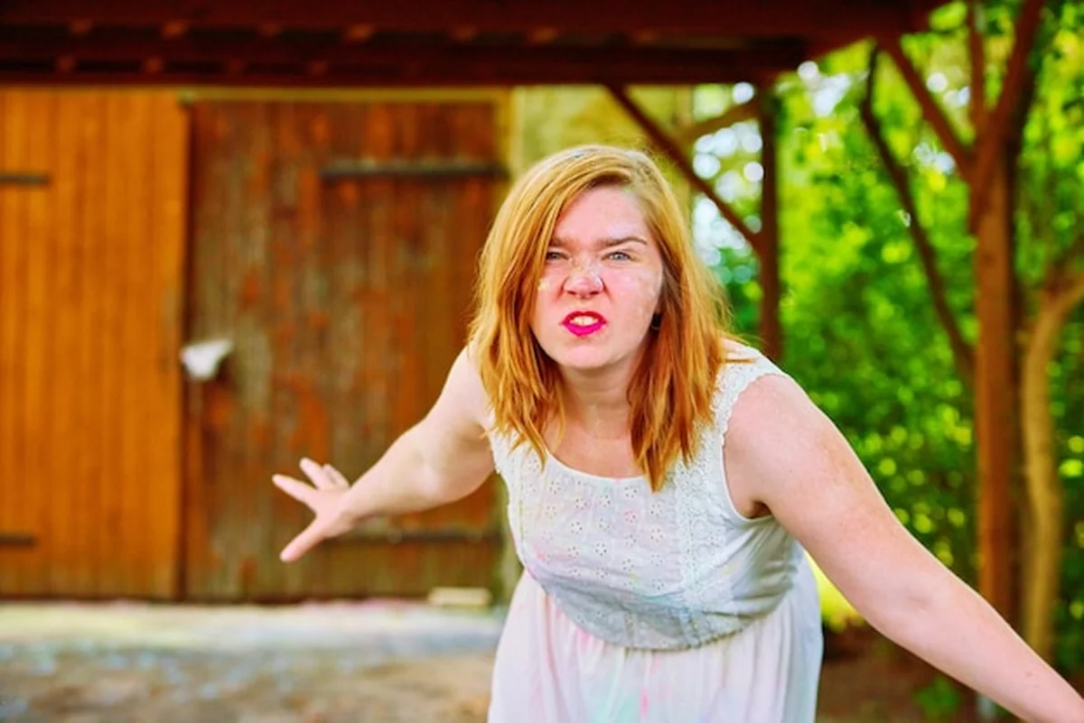 Kobieta robiąca minę stojąca przed inną twarzą