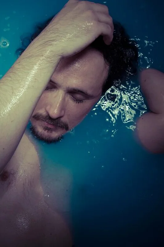 Mężczyzna w niebieskiej wannie pełnej wody