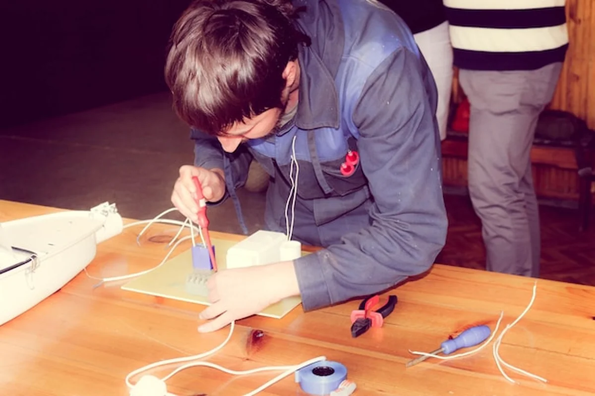 Mężczyzna elektryk zbiera obwód dużej białej lampy ulicznej