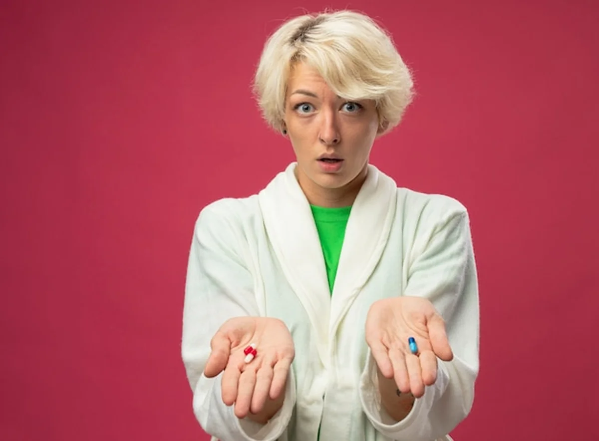 Osoba z manią trzymająca pigułki, wyglądająca na zdezorientowaną