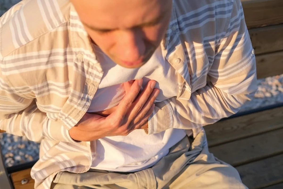 Osoba z zawałem serca trzymająca dłonie na klatce piersiowej