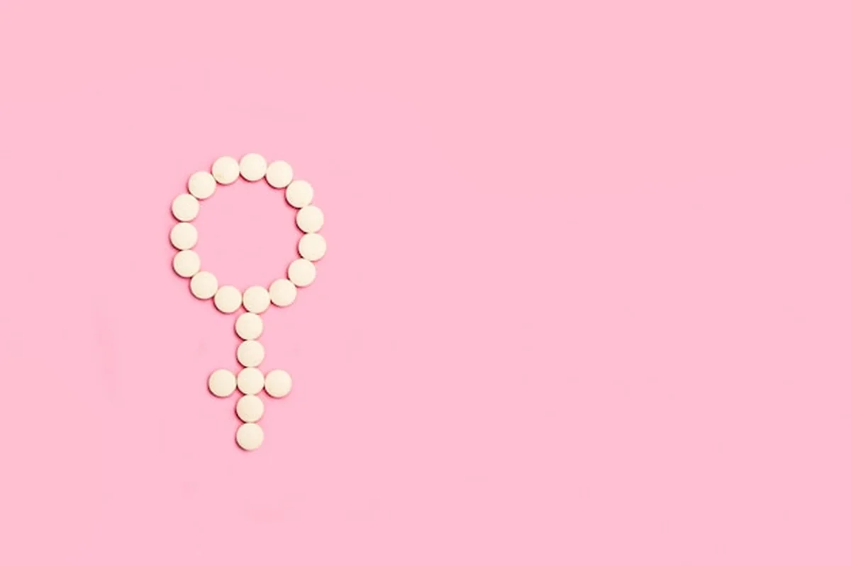 Tabletki medyczne w kształcie symbolu żeńskiego na jasnoniebieskim tle